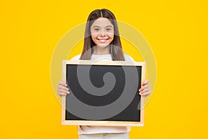 School sales board. Cheerful teenage girl kid hold blackboard chalkboard with copy space on yellow background. Happy