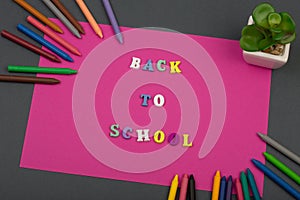 School set with pink paper, text & x22;Back to school& x22; of wooden letters and crayons