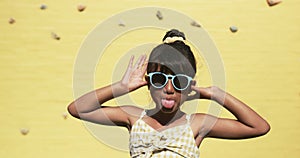 In a school setting, a young biracial student poses playfully, yellow background