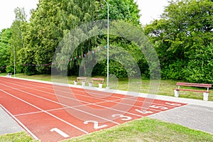 A school stadium running track with a red surface and six numbered lanes, athlete track