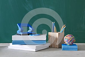 School stationery and books on table near chalkboard