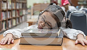 School student fall asleep while reading book in library or class from overwhelming learning or studying hard for exam