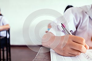 School student is taking exam and writing answer in classroom for education test concept