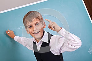 School student writing on blackboard at school