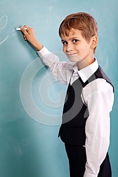 School student writing on blackboard at school