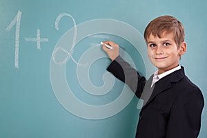 School student writing on blackboard at school