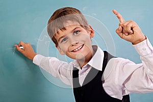 School student writing on blackboard at school