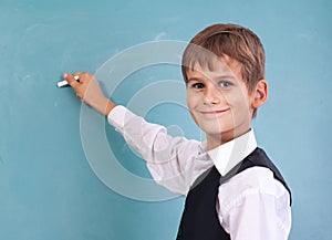 School student writing on blackboard at school