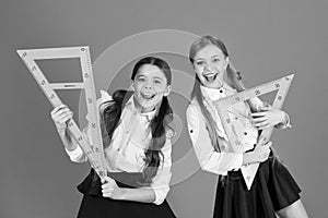 School students learning geometry. Kids school uniform on orange background. Pupil cute girls with big rulers. Geometry