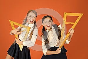 School students learning geometry. Kids school uniform on orange background. Pupil cute girls with big rulers. Geometry