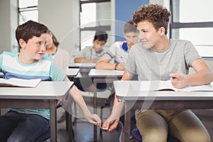 School students passing a chit in a secretive way inside the classroom photo