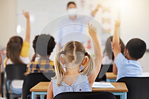 School students raising hands to volunteer, participate and answer during lesson while learning in a classroom. Teacher