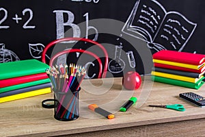 School supplies and accessories. Books, felt-tip pens, magnifying glass, red apple etc and a chalkboard on the