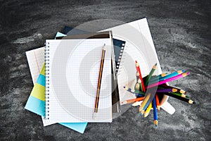 School supplies on black board background. Color pencils, calculator, rules and copybooks. Back to school concept. 1of September