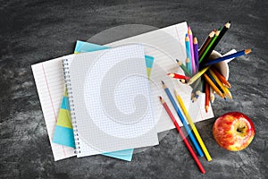 School supplies on black board background. Color pencils, calculator, rules and copybooks. Back to school concept. 1of September