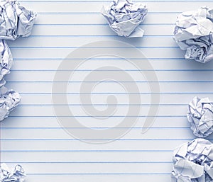 School supplies of blank lined notebook paper surrounded by more trashed balled up paper. Studying or writing mistakes concept