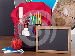 School Supplies in a Bookbag and Blank Chalkboard