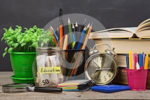 School supplies and glass jar with money for education on wooden table