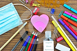 School supplies , a heart shape note pad ,a mouth mask and  liquid hand sanitizer