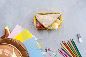 School supplies and lunch box with sandwich and vegetables. Back to school. Healthy eating habits concept - background layout with