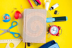 School supplies and mockup daybook on yellow background, top view.