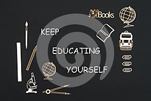 School supplies placed on black background with text keep educating yourself