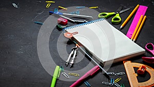 School supplies for school: notepad, pencils, pink ruler, compasses scattered on a gray table. Top view.