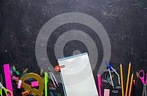 School supplies for school: notepad, pencils, pink ruler, compasses scattered on a gray table. Top view.