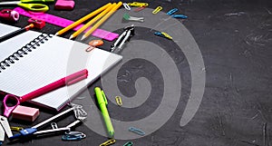 School supplies for school: notepad, pencils, pink ruler, compasses scattered on a gray table. Top view.