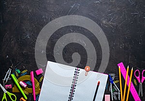 School supplies for school: notepad, pencils, pink ruler, compasses scattered on a gray table. Top view.