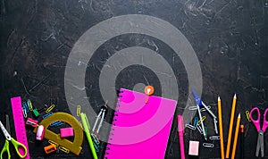 School supplies for school: notepad, pencils, pink ruler, compasses scattered on a gray table. Top view.