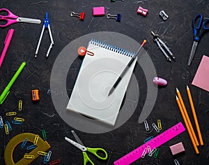 School supplies for school: notepad, pencils, pink ruler, compasses scattered on a gray table. Top view.