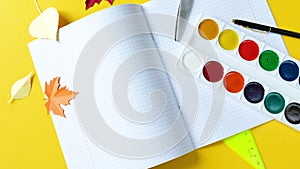 School supplies are spinning clockwise on a bright yellow background.