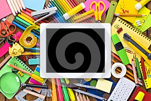 School supplies on wooden desk with digital tablet