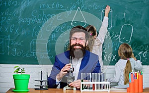 School teacher of biology. Man bearded teacher work with microscope and test tubes in biology classroom. Biology plays