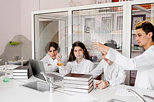 School teacher gives chemistry lesson to children in a laboratory with flasks with liquids for experiments. Education