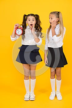 School time. Schoolgirls and alarm clock. Children school pupils. Knowledge day. Surprised shocked kids hold alarm clock