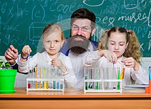 School time. Schoolgirls holding test tubes guided by teacher. School children performing experiment in science