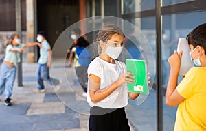 School tweens in medical masks in schoolyard during break