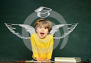 School wings and dream. Kid is learning in class on background of blackboard. Happy school kids. Talented child. School