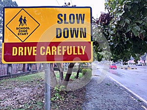 School zone slow Down sign board on the road side near school in H-8 Islamabad city of Pakistan in raining seasons after raining