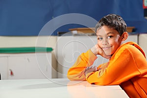 Schoolboy 10 wearing orange hoodie resting on clas