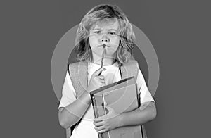 Schoolboy with backpack bag hold book. School children on isolated studio background. Thinking pensive kids, thoughtful