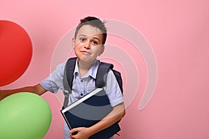 Concepts of happy back to school. Schoolboy with backpack holding book and multicolored balloons, cute smiling posing to camera