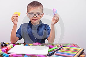 Schoolboy in a blue shirt sitting at the table. Boy with glasses on white background Concept back to school