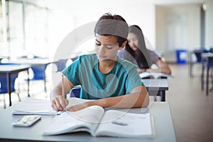 Schoolboy doing homework in classroom