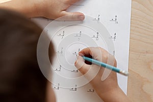 A schoolboy doing math lesson sitting at desk in the children room