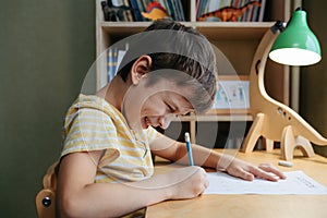 A schoolboy doing math lesson sitting at desk in the children room