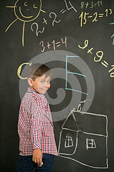 Schoolboy draws chalk on a school board