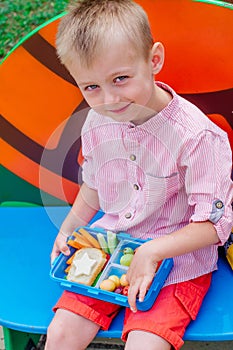 Schoolboy eating his lunch from lunch box outdoor